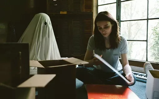 Na imagem temos os dos personagens, C e M, M lê um livro enquanto C a observa (C é um fantasma de lençol)